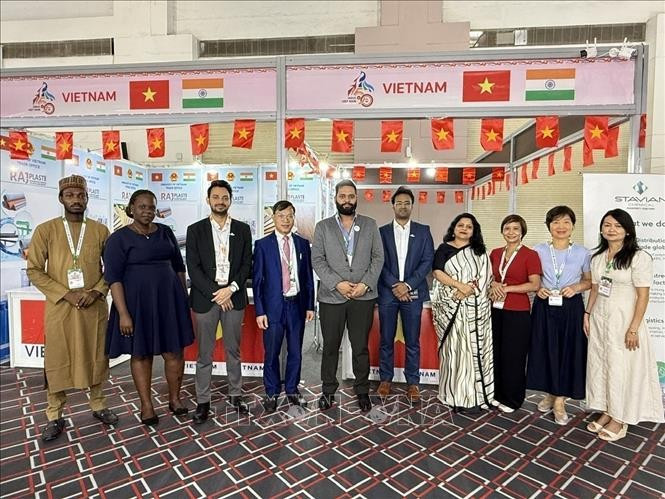 Trade Counselor Bui Trung Thuong (fourth from left) poses for a photo with domestic and international guests visiting the booth. (Photo: VNA) 