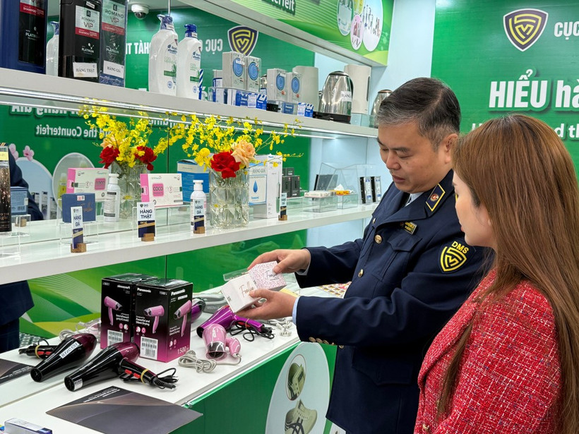 A market surveillance official guides a consumer on how to distinguish between genuine and counterfeit cosmetics. (Photo: VNA) 