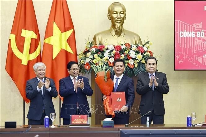 Prime Minister Pham Minh Chinh (second from left) and National Assembly Chairman Tran Thanh Man (far right) present the appointment decision and offer flowers to Nguyen Hong Dien. (Photo: VNA) 
