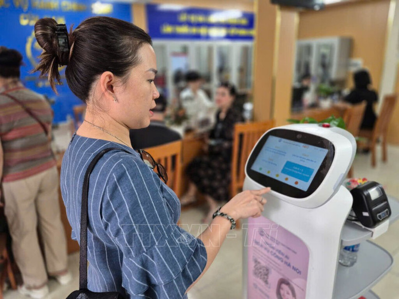 Woman experiences an AI-powered robot that applies AI technology to assist with administrative procedures at Cua Nam ward, Hanoi. (Photo: VNA) 