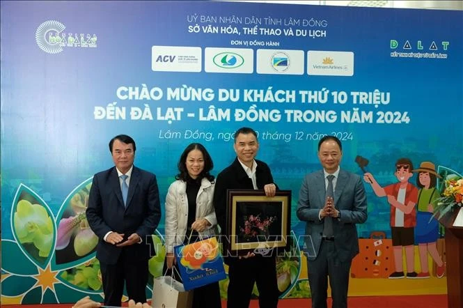 Leaders of Lam Dong province People's Committee present gifts to Nguyen Dang Dung (second from the right), a tourist from Hanoi - its 10 millionth tourist of the year (Photo: VNA)