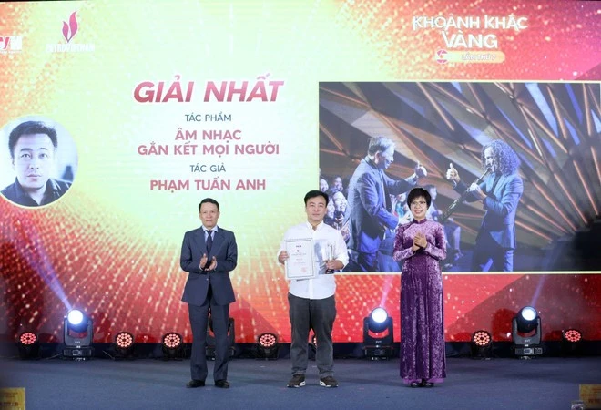 VNA General Director Vu Viet Trang (R) and Standing Vice Chairman of the Vietnam Journalists' Association Nguyen Duc Loi (L) present the first prize to Pham Tuan Anh at the event. (Photo: VNA) 