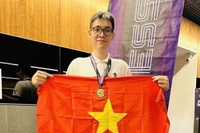 Le Tuan Minh holds the national flag to celebrate his win in rapid chess event of the Asian Mind Sports Conference & Festival which closed on November 15 in Singapore. (Photo: VNA)
