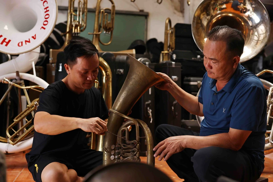 Nguyen Van Huong of the Trai Day brass band, Hai Minh commune, works with his son to inspect and repair brass instruments. (Photo: VNA)