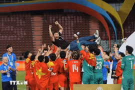 Vietnamese players share their joy with head coach Kim Sang-sik after the win on December 18. (Photo: VNA)