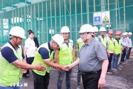 Prime Minister Pham Minh Chinh (R) encourages workers and engineers at the Vietnam Exhibition Fair Centre project site. (Photo: VNA)