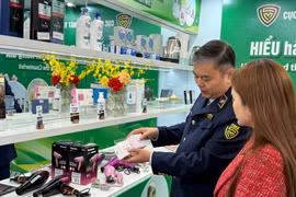 A market surveillance official guides a consumer on how to distinguish between genuine and counterfeit cosmetics. (Photo: VNA) 