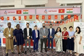 Trade Counselor Bui Trung Thuong (fourth from left) poses for a photo with domestic and international guests visiting the booth. (Photo: VNA) 
