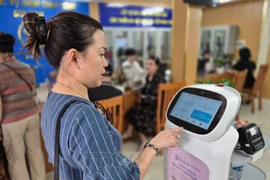 Woman experiences an AI-powered robot that applies AI technology to assist with administrative procedures at Cua Nam ward, Hanoi. (Photo: VNA) 