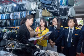 Tax officers give guidance to a small trader at a market. Under Decree No. 141/2026/ND-CP, the household businesses with annual revenue of 1 billion VND or less will not have to pay personal income tax and value-added tax. (Photo: VNA)