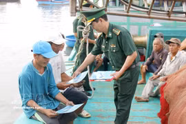 An officer of the Thanh Hai Border Guard Station, Lam Dong province, distributes leaflets on anti-IUU fishing regulations to fishermen. (Photo: VNA)