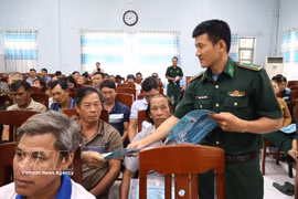 A border guard of Dak Lak distributes leaflets on anti-IUU fishing regulations to fishermen at the conference on October 15, 2026. (Photo: VNA)