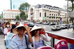 Foreign tourists use conical hats during their tour in Ho Chi Minh City. (Photo: VNA)
