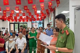 A police officer of Dong Da ward, Hanoi, gives guidance to citizens who come to receive the National Day gifts. (Photo: VNA)