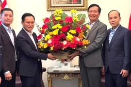 Lao Ambassador to Malaysia Thepthavone (L) presents a bouquet of fresh flowers to Vietnamese Ambassador Ding Ngoc Linh. (Photo: VNA)