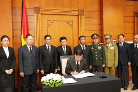 Party General Secretary and President of Laos Thongloun Sisoulith writes in the condolence book. (Photo: VNA)