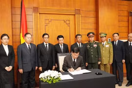 Party General Secretary and President of Laos Thongloun Sisoulith writes in the condolence book. (Photo: VNA)