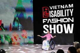 A model with physical challenge confidently showcase ao dai (Vietnamese traditional long dress) on the fashion runway. (Photo: VNA)
