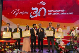 Vietnamese Ambassador to Germany Nguyen Dac Thanh (centre, right) and Vo Van Long, Chairman of Thang Long Group, pose for a commemorative photo with members of the group who received Certificates of Merit from the Embassy (Photo: VNA)