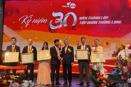 Vietnamese Ambassador to Germany Nguyen Dac Thanh (centre, right) and Vo Van Long, Chairman of Thang Long Group, pose for a commemorative photo with members of the group who received Certificates of Merit from the Embassy (Photo: VNA)