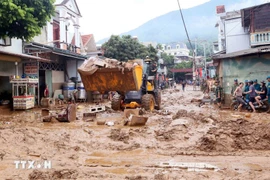 Excavators are deployed to help clear mud, fallen branches, and debris swept in by recent floods in Song Ma commune, Son La province. (Photo: VNA)