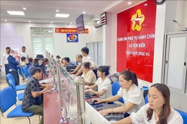 Civil servants and citizens carry out administrative procedures at the public administrative service centre of Tien Dien commune, Ha Tinh province. (Photo: VNA)