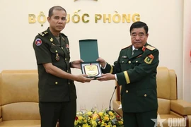 Major General Nguyen Ba Luc (R) presents a gift to Lieutenant General Nim Balene. (Photo: Qdnd.vn)