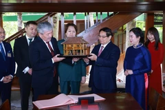 Prime Minister Pham Minh Chinh presents a model of President Ho Chi Minh’s stilt house to Prime Minister Adylbek Kasymaliev. (Photo: VNA)