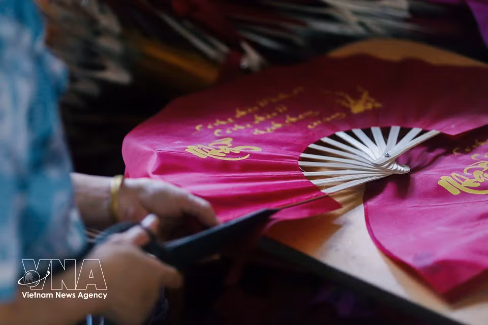 Cutting and shaping the fan paper is a key aesthetic stage in the process. (Photo: VNA)
