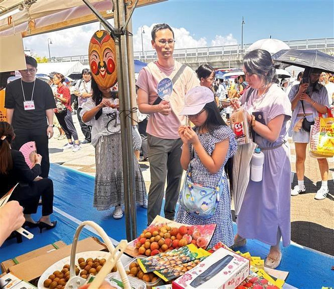 A Japanese family tastes fresh Vietnamese lychees at the festival (Photo: VNA) lychees-6178.jpg.webp