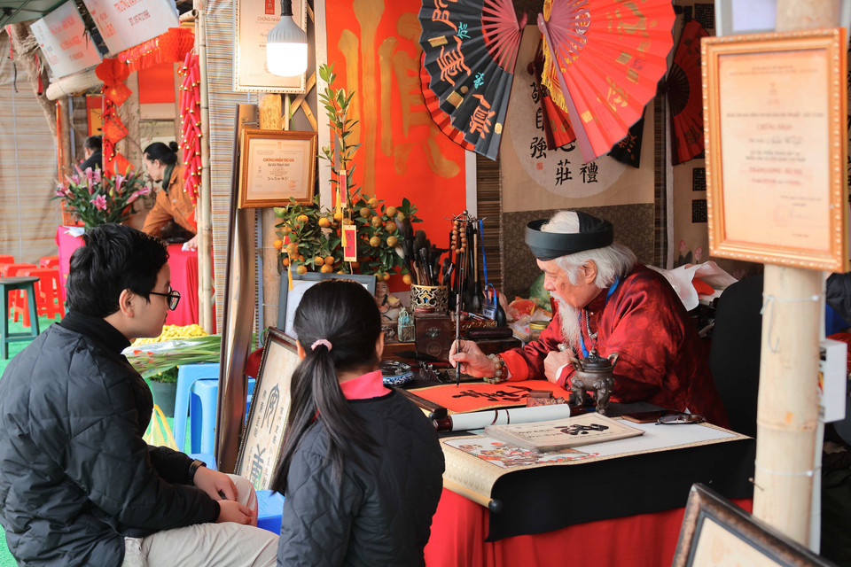 People come to the scholars and tell them about their wishes for the New Year, which will then be written down in Chinese script. People believe that those calligraphic scripts will help turn their wishes into reality. (Photo: VNA)