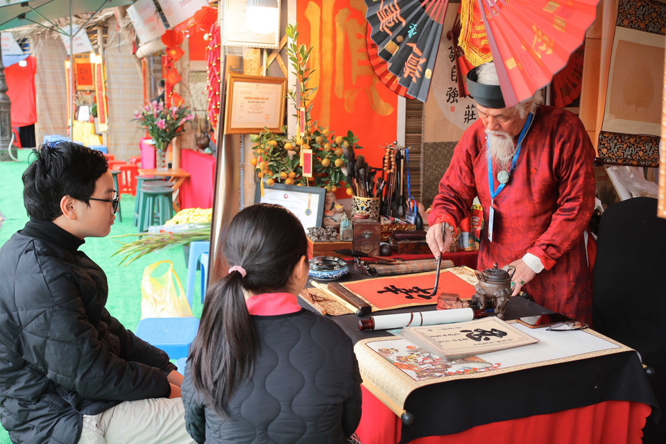 People come to the scholars and tell them about their wishes for the New Year, which will then be written down in Chinese script. People believe that those calligraphic scripts will help turn their wishes into reality. (Photo: VNA)
