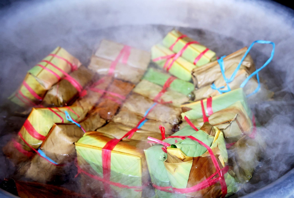 For any Vietnamese, the image of a pot of “banh chung”, fragrant with dong leaves, placed on a stove with bright flames to warm the winter chill has become a familiar sight every Tet. (Photo: VietnamPlus)