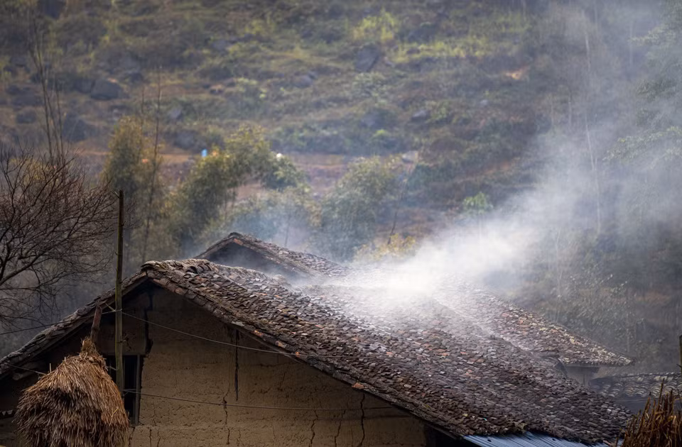 Kitchen smoke drifts over a rammed-earth house’s yin-yang tiled roofs. (Photo: Khanh Hoa – VNA)