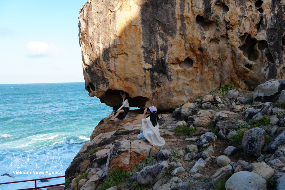 A tourist poses with a uniquely shaped rock formation at Hang Rai. (Photo: VNA)