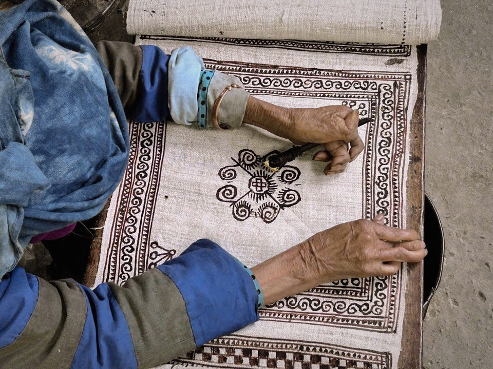 Beeswax patterns are drawn on raw hemp cloth. (Photo: VNA)