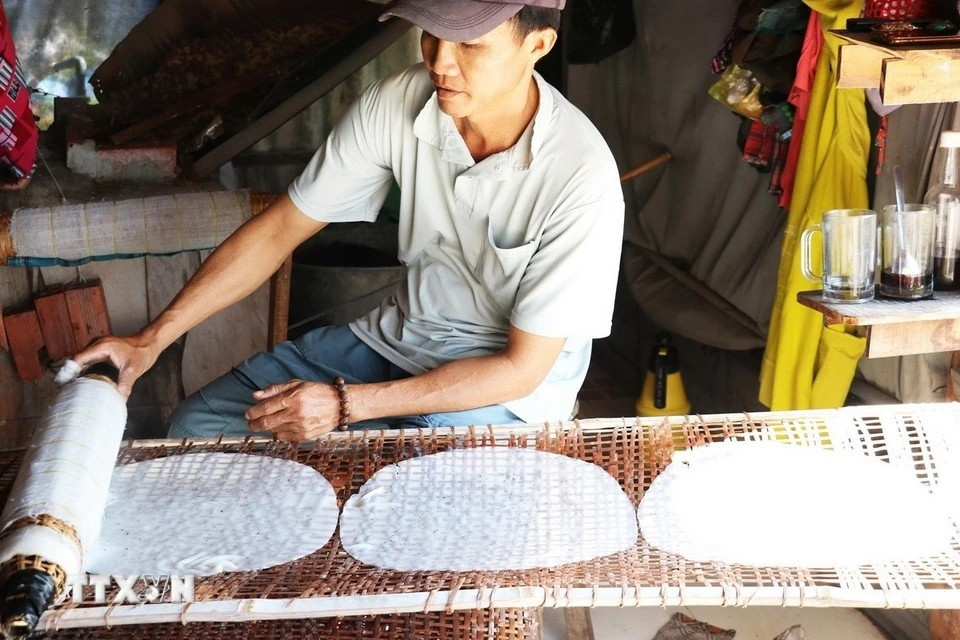 Nguyen Van Tai, a resident of Hau Thuan hamlet, Hau Thanh commune, carefully places freshly made rice paper onto bamboo racks for sun drying. (Photo: VNA)