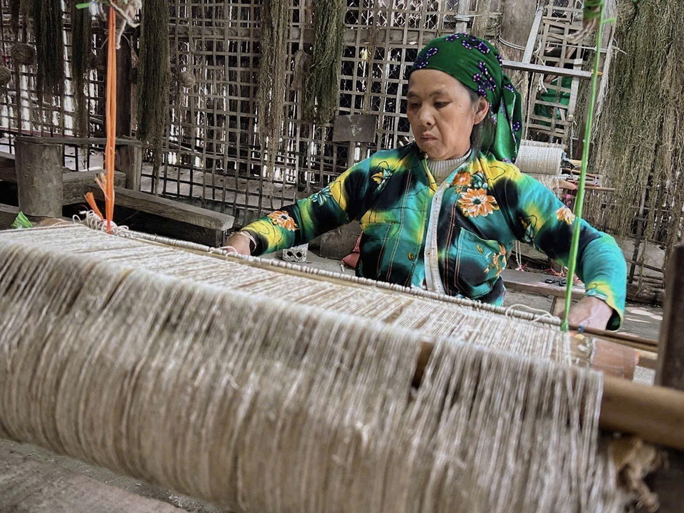 A Hmong woman in Lung Tam village hand-weaves fabric on traditional wooden looms. (Photo: VNA)
