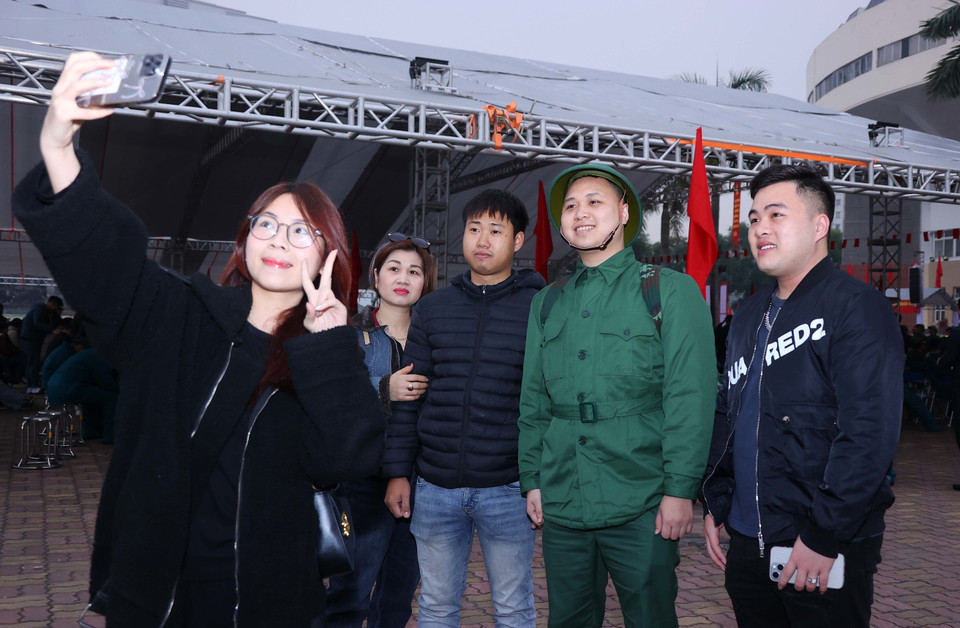 Friends and family take commemorative photos with recruits at the enlistment handover ceremony. (Photo: VNA)
