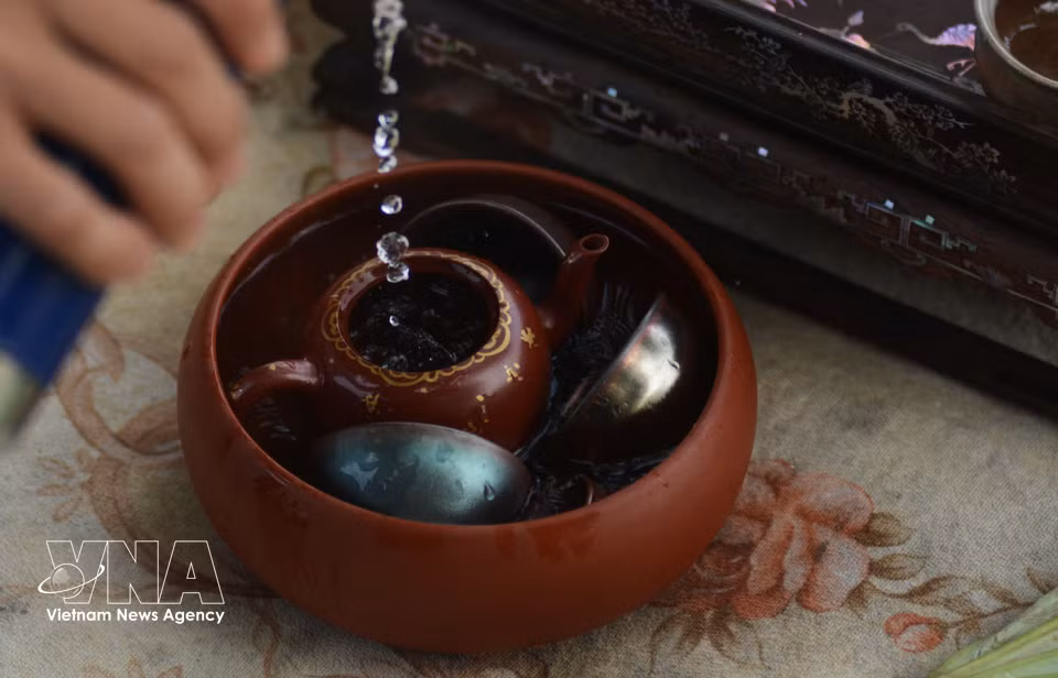 Before preparing lotus tea, the artisan carefully cleans and warms the teapot and cups. (Photo: VNA)