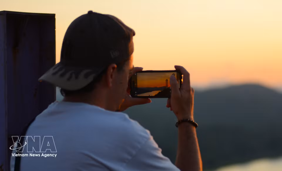 Foreign visitor takes photo of the scenery around Vong Canh hill at sunset. (Photo: Van Dung/VNA)
