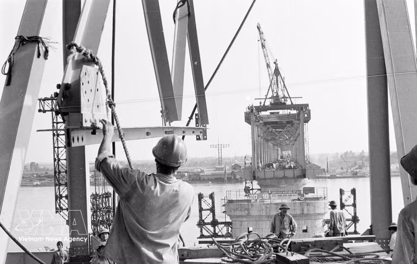 Alongside the nation’s history and development are numerous projects bearing the imprint of Vietnamese intellect in applied research, as well as works that embody the collective wisdom, resilience, and dedication of Vietnamese workers who quietly contribute to the community. In the photo: Workers from Bridge Company No. 11 install the final spans of Thang Long Bridge (1984). (Photo: VNA)