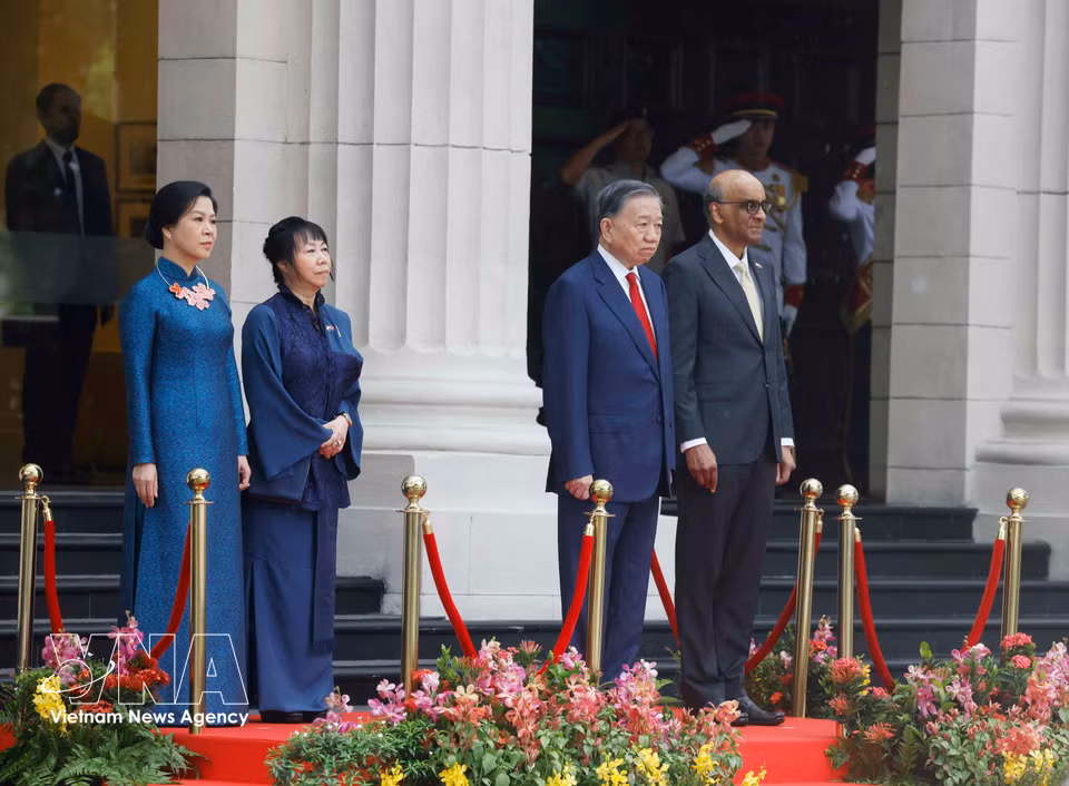 Party General Secretary and State President To Lam and Singaporean President Tharman Shanmugaratnam stand on the podium as the military band plays the national anthems of the two countries. (Photo: VNA)