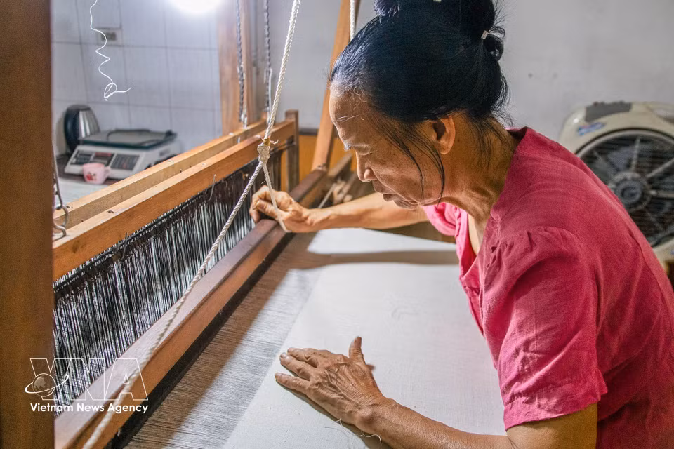 A woman in the craft village diligently weaves fabric at her loom. (Photo: VNA)