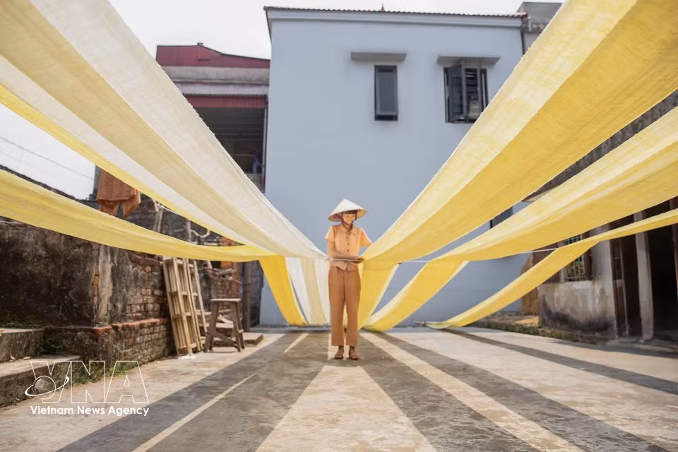The fabric is dried under natural sunlight, an important step that helps make the silk fibres tighter and more durable. (Photo: VNA)