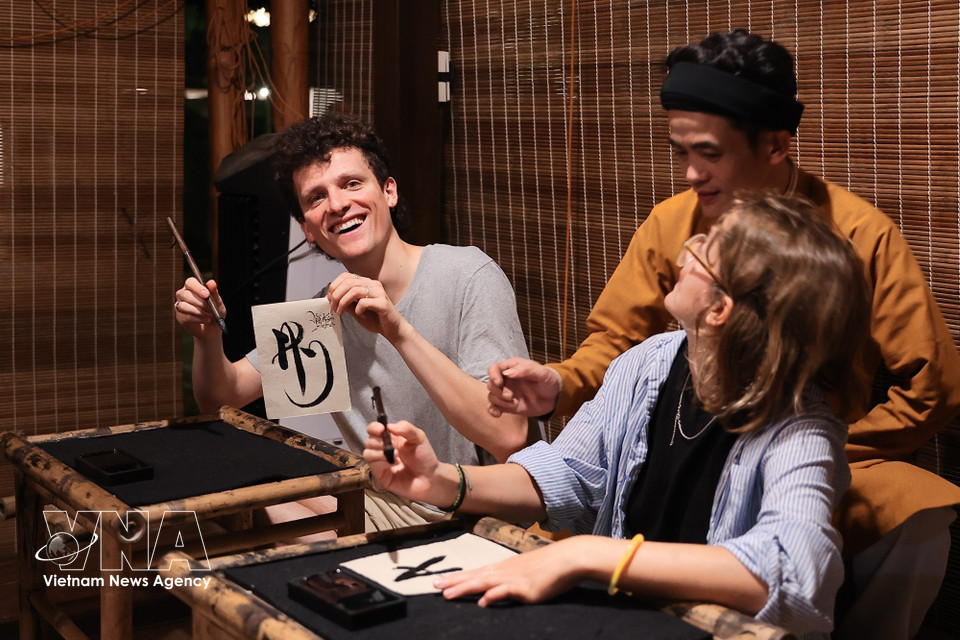International visitors take part in a calligraphy-writing experience at the Temple of Literature. (Photo: VNA)