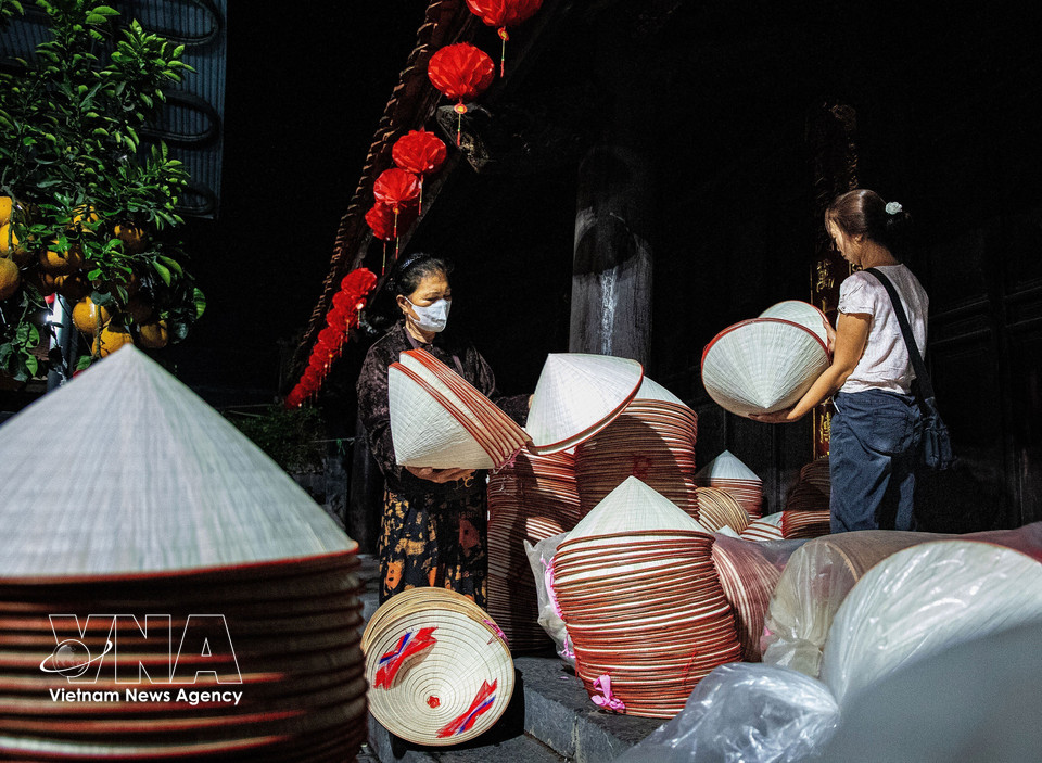 Villagers bring stacks of conical hats to the communal yard for sale during the early-morning market. (Photo: VNA)