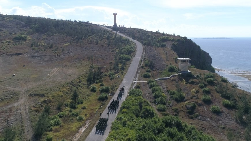 Thirty-four soldiers, including border guards, naval soldiers and coastal police, bring the national flag to Thoi Loi peak, the highest point on Ly Son island, for a flag-raising ceremony. (Photo:Vietnamplus)