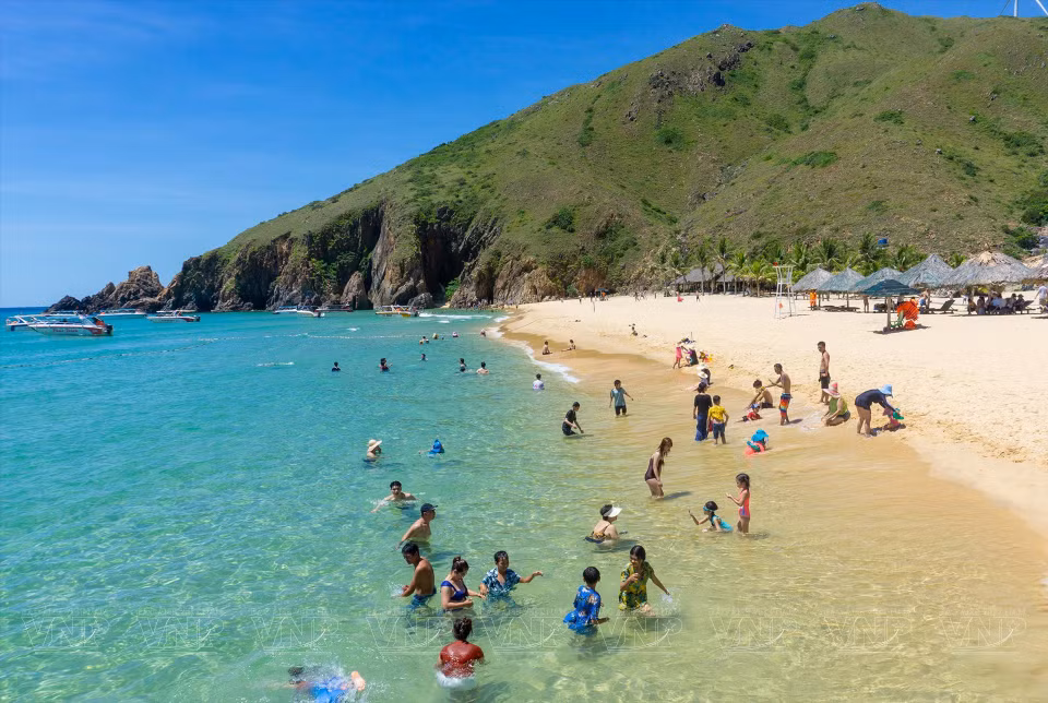 Tourists relax in the cool turquoise waters of Ky Co Beach which is surrounded by magnificent rocky mountains and the turquoise sea. (Photo: VNP/VNA)