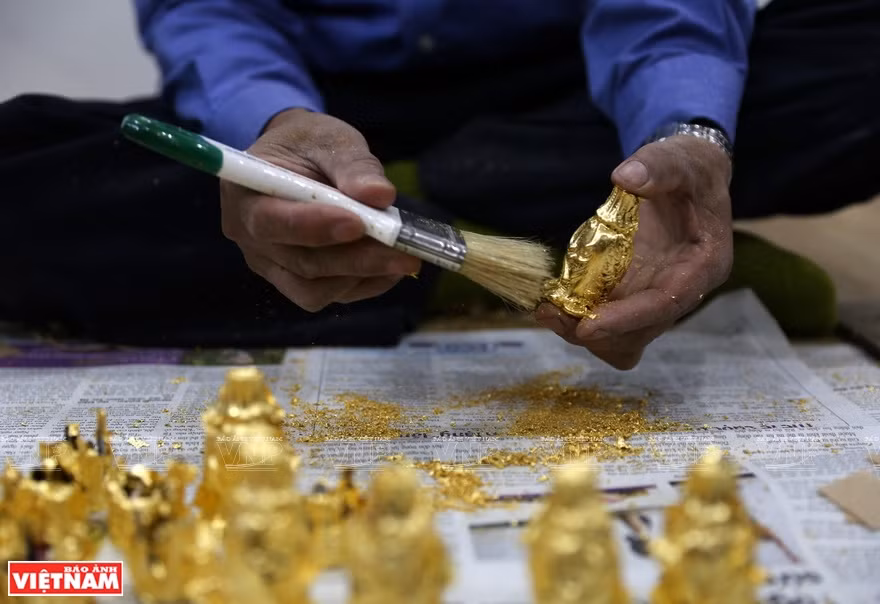 To create a smooth and shiny golden coat for ancient-looked products, gilding craftsmen need to overlay the products with super-thin gold leaves while the paintwork is still wet (Photo: VNA)